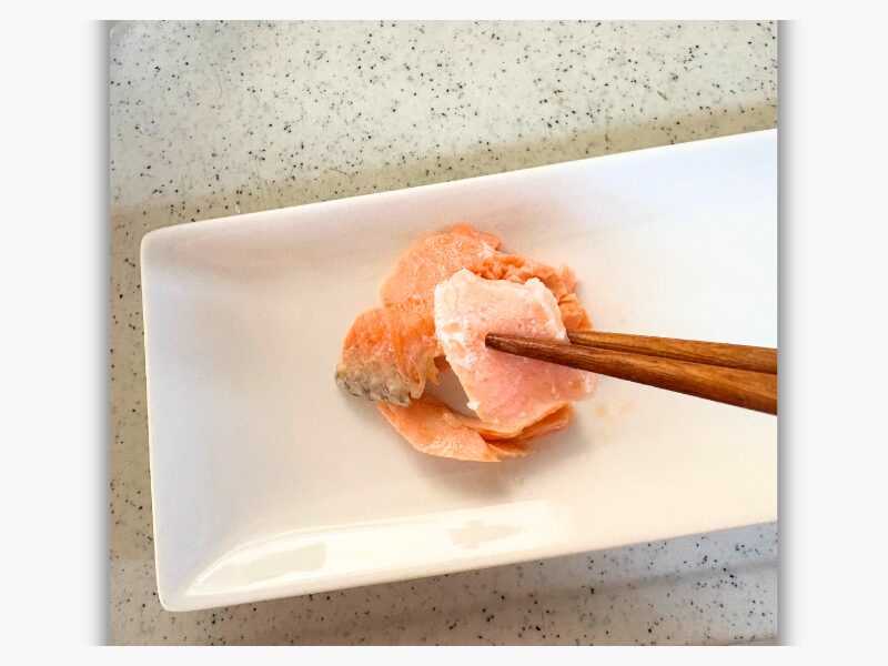 箸で持ち上げた湯煎した鮭の切り身